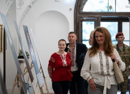 Fotografia. Wernisaż wystawy piękno jedności. ludzie oglądają fotografie stojące na sztalugach pod ścianą holu głównego willi Decjusza.